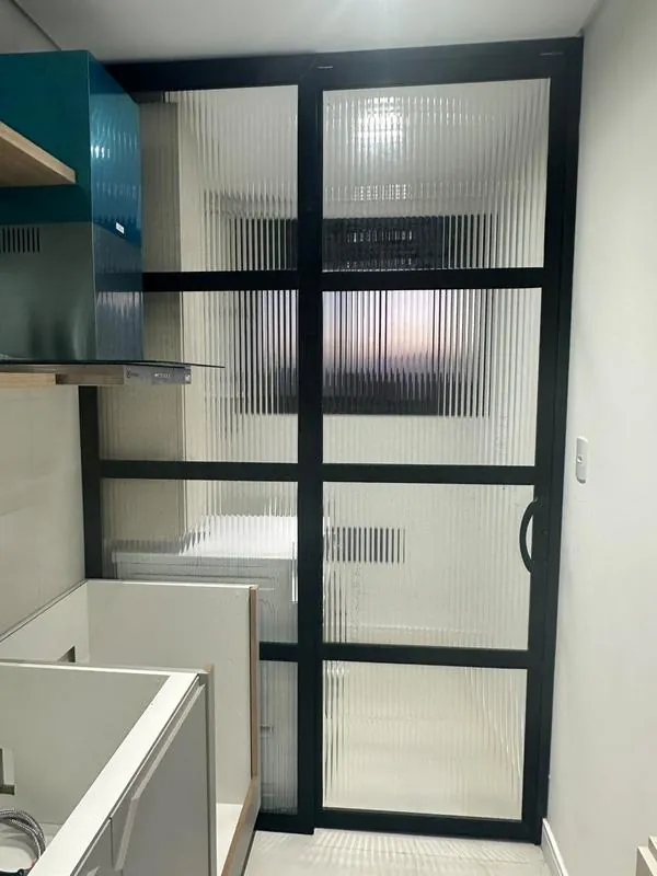 Porta de correr com vidro canelado e perfil preto – separação de ambientes